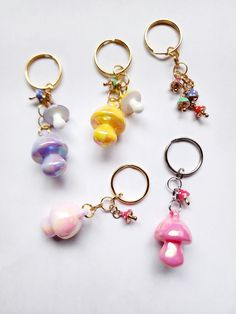 four key chains with charms on them sitting next to each other in different colors and shapes