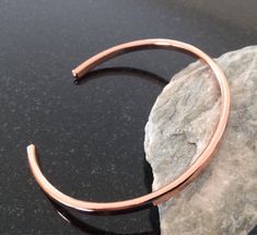 a close up of a metal bracelet on a rock