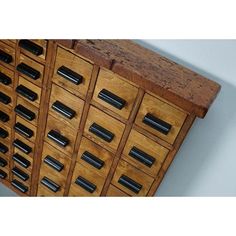 a wooden cabinet with many drawers and metal pulls on the top shelf, in front of a white wall