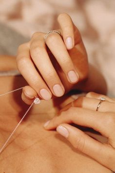 a woman is getting her nails done while laying on the bed with a diamond ring