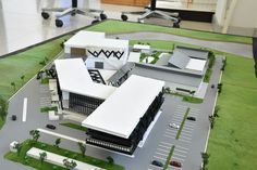 an architectural model of a building with cars parked in the parking lot next to it