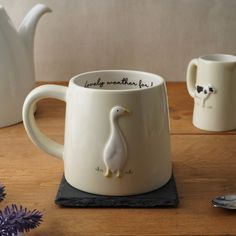 two coffee mugs sitting on top of a wooden table