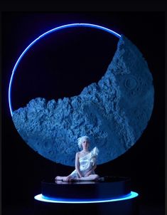 a woman sitting on the ground in front of a blue moon