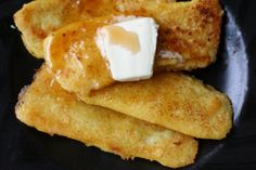 some fried food on a black plate with butter and sauce in the middle, ready to be eaten