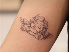 a small tattoo on the arm of a girl with an angel holding a teddy bear