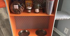 an orange shelf with two metal bowls on it and spices in the bottom one is empty