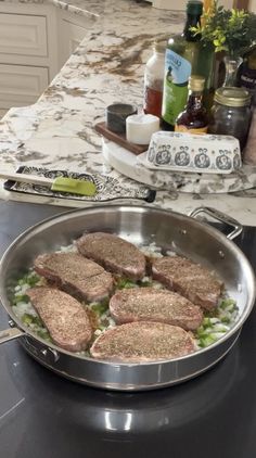 some meat patties are cooking in a pan on the stove top next to an oven