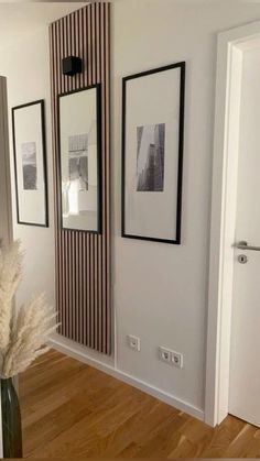 a vase with some flowers in it next to two pictures on the wall and a radiator