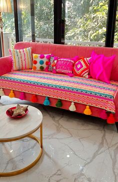 a living room with a pink couch and colorful pillows on top of it's back