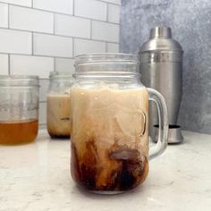 a jar filled with liquid sitting on top of a counter next to a blender