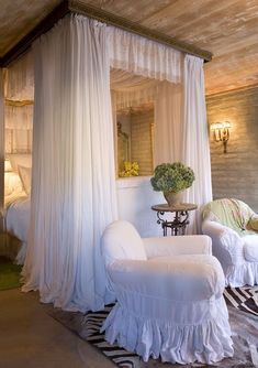 a bedroom with two white chairs and a canopy bed