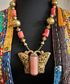 Tibetan Nepalese handmade huge repousse Butterfly vintage brass pendant amulet with beautiful Tibetan orange coral & brass  Nepalese beads unique bohemian statement necklace. This is a large chunky necklace that is bold and beautiful and guaranteed to make a statement! This necklace measures 25" in length.  Beautiful handmade vintage hammered brass beads and big chunky rare orange coral from nepal beaded with a focal handmade Tibetan orange coral repousse butterfly amulet silver pendant.  The bu Handmade Artisan Coral Beaded Necklaces, Bohemian Brass Jewelry With Large Beads, Handmade Coral Beaded Necklaces For Spiritual Use, Handmade Coral Bohemian Beaded Necklaces, Handmade Coral Beaded Necklaces Spiritual Style, Handmade Brass Beaded Necklaces For Festivals, Bohemian Coral Beaded Necklace For Gifts, Unique Bronze Beaded Necklaces For Festival, Bohemian Brass Beaded Necklaces For Festivals