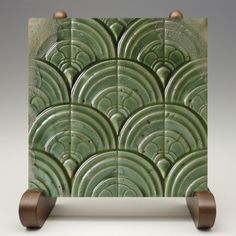 an art deco tile with wooden wheels on the bottom and green tiles in the middle