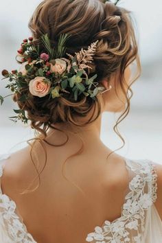 a woman with flowers in her hair is wearing a wedding dress and looking off to the side