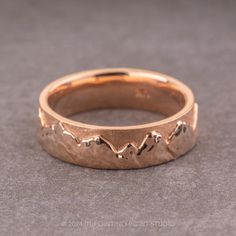 a gold wedding band with mountains on it