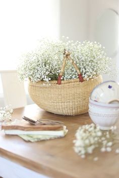 a basket filled with baby's breath sitting on top of a table next to a bowl