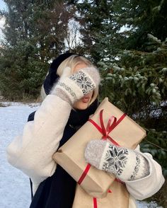 a woman wearing mittens and gloves holding a wrapped present