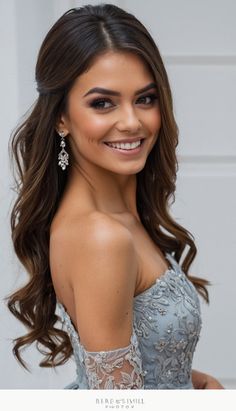 a woman with long hair wearing a blue dress and smiling at the camera while standing in front of a white door