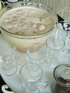 a table topped with lots of glasses filled with liquid next to jars and spoons