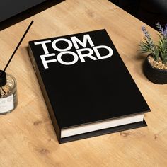 a black book sitting on top of a wooden table next to a potted plant