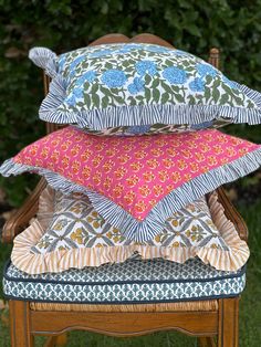 three pillows stacked on top of each other in front of a chair with green grass