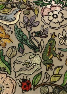 an embroidered fabric with various flowers and bugs on the side, all in different colors