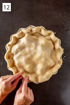 a pie crust being prepared to be baked in the oven with two hands on top