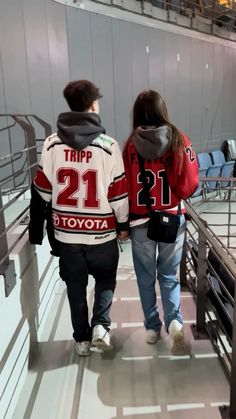 two people walking down a flight of stairs wearing jackets that say trip 21 and toyota