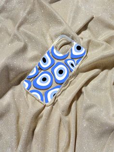 a cell phone case sitting on top of a bed covered in a tan sheet with blue circles