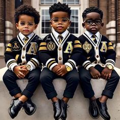 three young boys in black and gold uniforms sitting on a ledge with their arms crossed