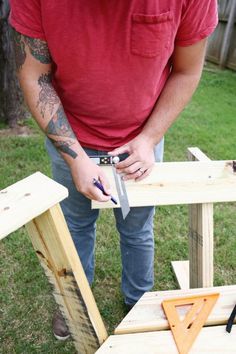 a man holding a pair of scissors in his hand while standing next to a wooden bench