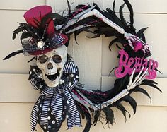 a halloween wreath on the front door of a house that is decorated with black, white and pink decorations