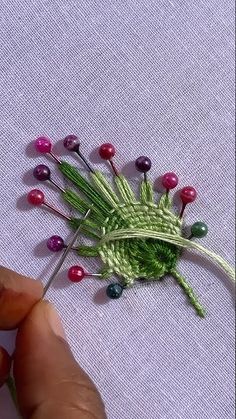 someone is working on an art project with yarn and beads in the shape of a flower