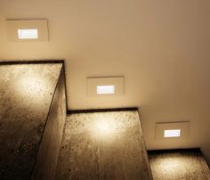 three recessed lights on the side of a wall in a room with wood floors