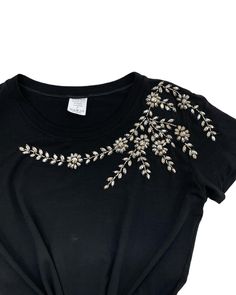 a black t - shirt with white flowers on the chest and gold trimmings