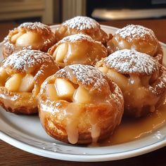 several pastries on a white plate covered in powdered sugar and apple toppings