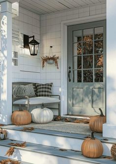 a porch decorated for fall with pumpkins on the steps