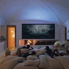 two people laying on bean bags in front of a harry potter movie poster and fireplace