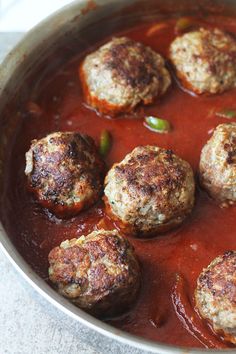 some meatballs are cooking in a red sauce