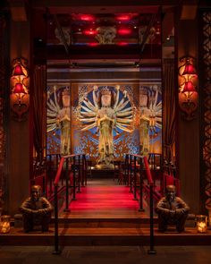 the interior of a restaurant with red lighting and artwork on the wall, along with candles