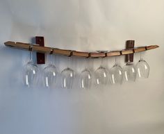 five wine glasses are hanging from a wooden rack on the wall, and one is empty