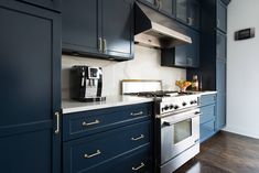 a kitchen with dark blue cabinets and white counter tops, gold pulls on the oven