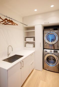 a washer and dryer in a small room with white cupboards, wood flooring