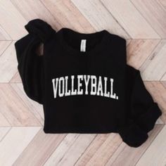 a black sweatshirt with the word volleyball on it sitting on top of a wooden floor