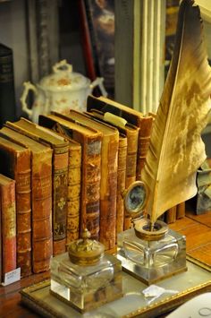 an old book set on a table with a feather quill and other books in front of it