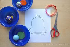 a paper with a drawing of a bell on it next to some bowls and scissors