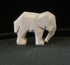 an origami elephant standing on top of a black surface with its trunk in the air