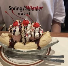 a banana split with ice cream, chocolate sauce and cherries in a glass bowl