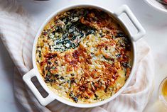 a casserole dish with spinach and cheese in it on a white table