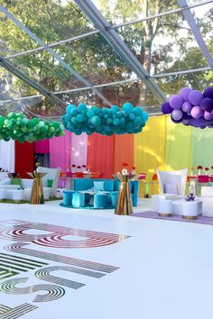 an outdoor party with colorful balloons and decorations on the ceiling, in front of a tent